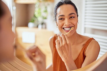 Woman smiling while brushing her teeth