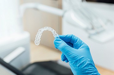 Dentist holding clear aligner with blue glove