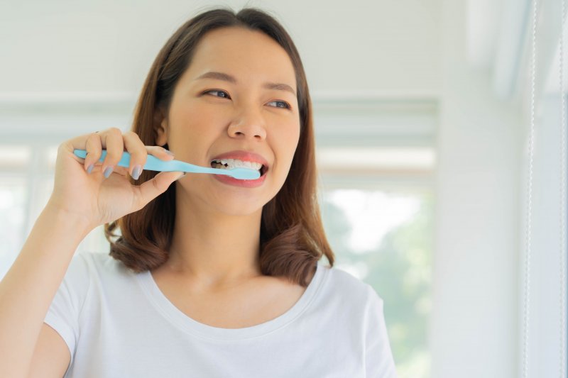 person using toothpaste for veneers to brush teeth