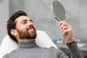 Patient using a mirror to admire his fantastic new dental crown