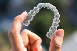 Close up of someone holding up an Invisalign tray