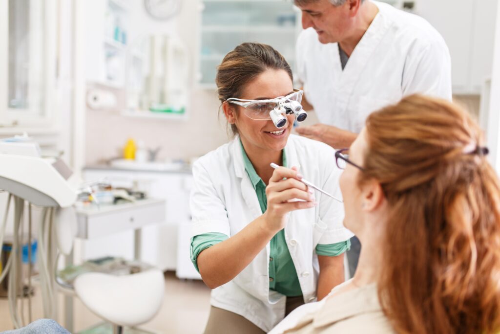 Smiling dentist talking to patient during exam